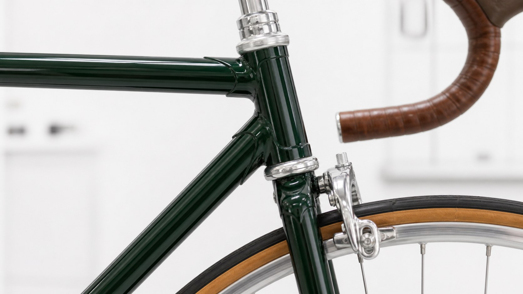 Forest-green bicycle head tube and polished front brake detail