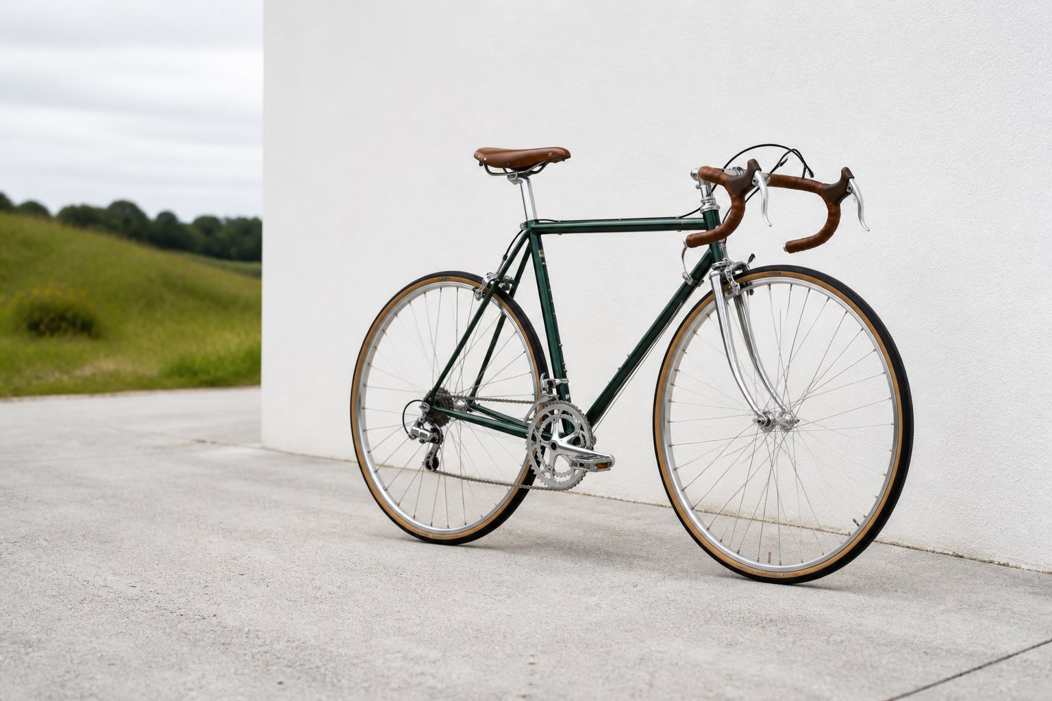 Restored forest-green bicycle beside a white wall and open landscape